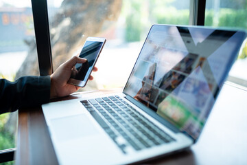 businessman uses smartphone to share internet connection to work on laptop at coffee shop