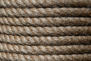 Wall Mural - Natural jute hemp rope rolled into a coil, closeup. Brown spool of linen rope texture on the background