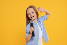Cute Little Girl With Microphone Singing On Yellow Background