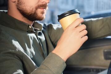 Canvas Print - Coffee to go. Man with paper cup of drink in car, closeup