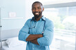 Portrait of happy african american male doctor wearing blue shirt and stethoscope in hospital room
