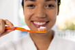 © WavebreakMediaMicro - Portrait of happy biracial woman in bathrobe holding brush with tooth paste in sunny bathroom
