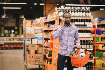 African man shopping at supermarket. Handsome guy holding shopping basket