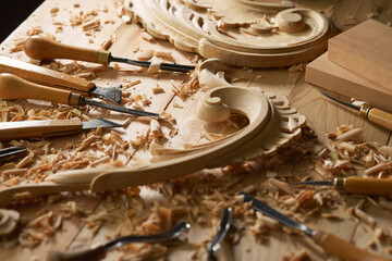 Wall Mural - Hands of craftsman carve with a gouge in the hands on the workbench in carpentry. Wood carving tools close-up