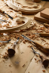 Wall Mural - Experienced carpenter shapes wood with a chisel. Wooden table with a set of different chisels for woodcarving