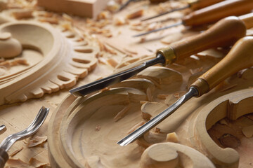 Sticker - Hands of craftsman carve with a gouge in the hands on the workbench in carpentry. Wood carving tools close-up