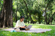 Happy Asian senior woman using laptop for working online outside office. Elderly retirement using laptop for learning new skill and freelance working in park, senior lifestyle with technology