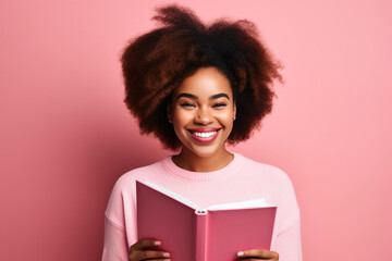 Portrait of gorgeous positive African American person toothy smile hold opened book isolated on pink color background