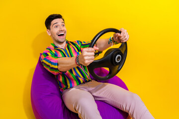 Poster - Portrait of driving car simulator young crazy funny man hold steering wheel unreal speed in game isolated on yellow color background