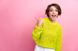 © deagreez - Photo of young surprised girl in yellow knitted stylish clothes pointing finger banner last pieces left isolated on pink color background