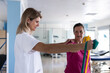 © Martin - Physiotherapist is teaching her patient how to do rehabilitation exercises with a rubber band. She has her left hand on her shoulder.