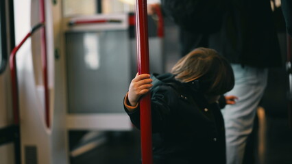 whimsical Little traveler on a train, clutching a metal support bar and twirling around it. A snapshot of childhood joy, making the best of the commute with innocent play