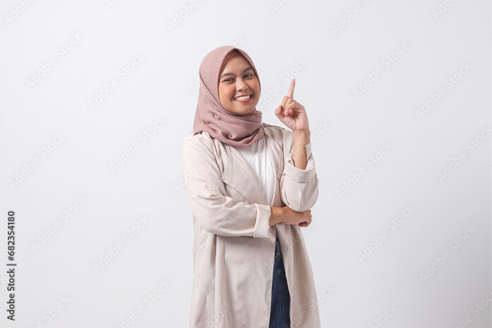 Portrait of excited Asian hijab woman in casual suit pointing up her ...