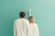 Back of fashion family couple in white clothes looking at the Cross of Jesus. Church, worship, christianity concept. Men and woman, husband, wife, bride, groom, guy and girl on pastel background