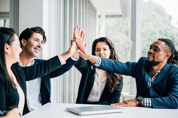 Wall Mural - The office atmosphere is charged with positivity as a diverse group of colleagues engages in high-fives during a productive meeting, showcasing their dedication to teamwork and shared success.