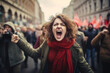 Young woman yelling and shouting in a crowd of protesters. Activists protesting on the street. People publicly demonstrating opposition. Gloomy city scenery.