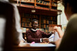 © Marko Geber - Young male student having discussion in library study hall
