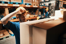 Young Man Putting Helmet On In Warehouse