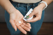 Young woman holds white pill in a hand, take medicine from blister pack, close-up view