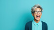 © Synthetica - Middle age senior woman with blue eyes wearing elegant coat and glasses over blue background very happy and excited looking frustrated expression with victory screaming, smiling and.