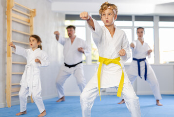 Kata karate teacher conducts classes and performs movements and fighting techniques together with active family students to prepare them for competitions.