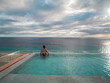 Back view of a woman standing in an infinity pool