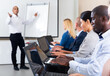 © JackF - Side view of young african american businessman working on laptop with group of colleagues during corporate seminar