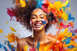 Laughing woman with splashes of colorful paint on her body and face.
