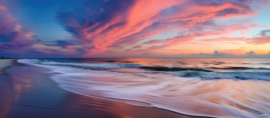 Poster - In the midst of summer, with the sky ablaze in hues of pink and orange, the tranquil beach became a canvas for nature's artistry, as water and clouds met in a harmonious dance, while the line where