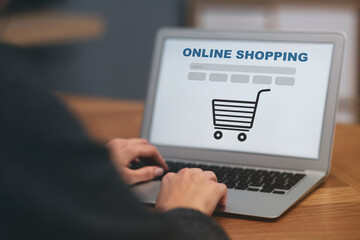 Woman using laptop for online shopping at wooden table, closeup