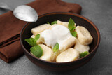 Fototapeta  - Bowl of tasty lazy dumplings with sour cream and mint leaves on brown table