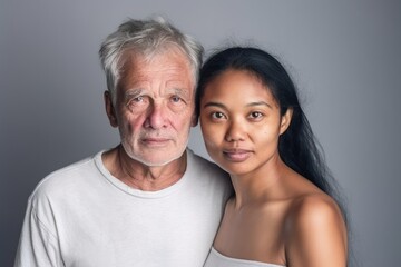 Wall Mural - Smiling senior caucasian man posing with a young woman looking at the camera 