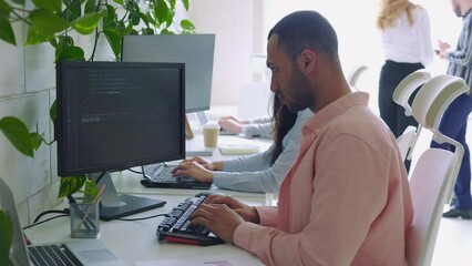 Multi Ethnic Computer Programmer Writing a Code in an Office.