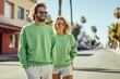 © Barbara Taylor - a young couple wearing a plain green crewneck sweatshirt and jean shorts walking down a street with palm trees