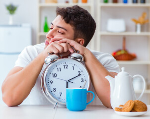 Wall Mural - Man with alarm clock falling asleep at breakfast