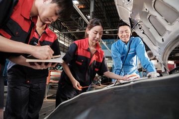 Asian male professional automotive supervisor advises and inspects a mechanic worker woman about liquid engine oil at car garage, service maintenance, and fix specialist occupations auto industry.