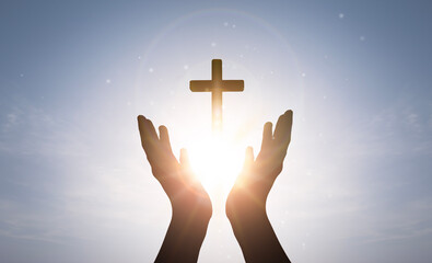 Wall Mural - Brightly shining sunlight and Silhouette of cross in human hand