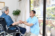 介護士の中年男性と車椅子に乗る高齢者男性