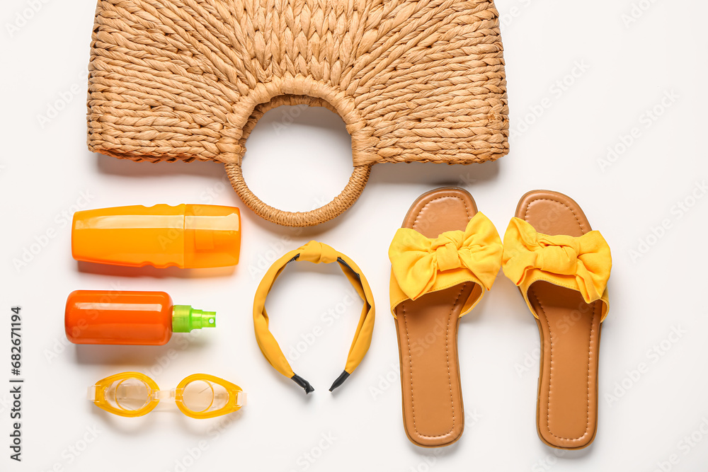 Bottles of sunscreen cream with beach accessories on white background