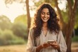 © Tony - Close up beautiful young indian woman smiling and looking at mobile phone Generative AI
