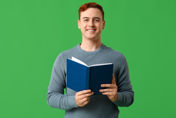 Wall Mural - Smiling handsome man with book on green background