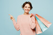 canvas print picture - Young woman wear beige knitted sweater casual clothes hold in hand paper package bags after shopping point aside isolated on plain light pastel blue cyan background. Black Friday sale buy day concept.
