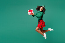 Full Body Merry Little Kid Teen Girl Wear Hat Casual Clothes Posing Hold Present Box With Gift Ribbon Bow Isolated On Plain Green Background Studio Portrait. Happy New Year Christmas Holiday Concept.