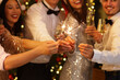 © Pixel-Shot - Group of friends with champagne and sparklers celebrating New Year at party, closeup
