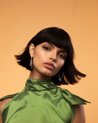 Canvas Print - photo of a young Latino brunette woman with modern neon makeup and a modern haircut wearing a sage green abstract  dress, fashion shoot - Generative AI