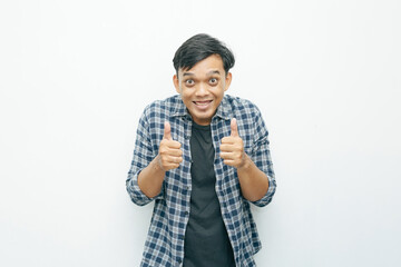 Portrait of young Asian Indonesian man smiling and showing two thumbs up as yes or successful gesture expression