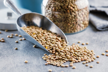 Sticker - Uncooked lentil legumes in scoop on kitchen table.