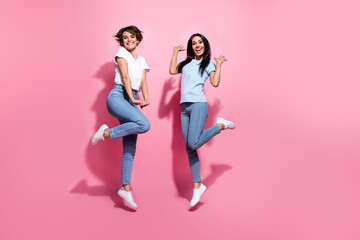 Sticker - Full length body photo of optimistic young positive girls jump have fun happiness good mood sportive isolated on pink color background