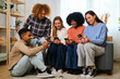 © Ladanifer - Group of young flat mates using their smartphone together at shared apartment.