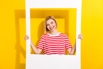 Poster - Portrait of gorgeous pretty girl with short hairdo wear stylish t-shirt hands hold photo frame isolated on bright yellow background